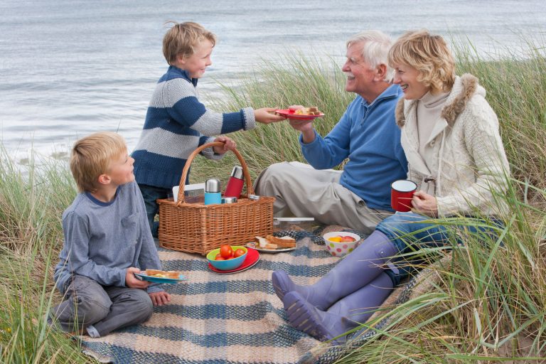 grandmother and grandfather having a picnic with two grandchildren on dune overlooking sea