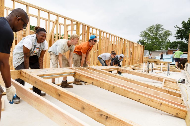 six volunteers lifting frame for a wall for a home